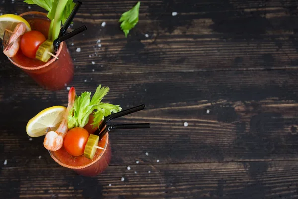 Kokteyl Bloody Mary garnitürleri ile gözlük. Koyu ahşap arka plan kopya alanı ile domates Bloody Mary baharatlı içki.