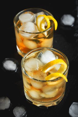 Viski ya da limonlu buzlu rom büküm siyah taş zemin üzerine.