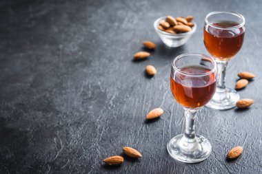 İtalyan likörü Amaretto badem siyah taş arka planda, kopya alanı ile