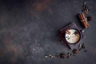 Geleneksel Hint masala chai çay malzemelerle seramik Kupası'nda. Tarçın, kakule, anason, baharatlı siyah çay süt üzerinde koyu arka plan, kopya alanı ile.