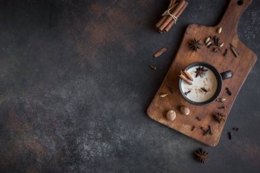 Geleneksel Hint masala chai çay malzemelerle seramik Kupası'nda. Kopya alanı rustik koyu arka plan üzerinde süt ile baharatlı siyah çay.