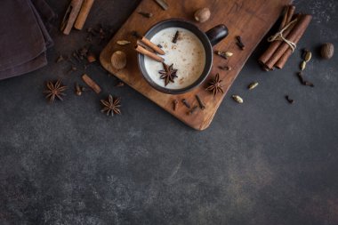 Geleneksel Hint masala chai çay malzemelerle seramik Kupası'nda. Kopya alanı rustik koyu arka plan üzerinde süt ile baharatlı siyah çay.