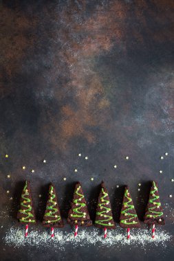 Yeşil buzlanma ve şenlikli sprinkles, üstten görünüm, Noel ağaçları şeklinde çikolata kek alanı kopyalayın. Tatlı Noel ya da kış tatil Pastacılık gıda kavramı.