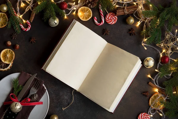 Christmas Cookbook or Menu on dark table. Empty cook book, recipes book with festive Christmas decor and spices.