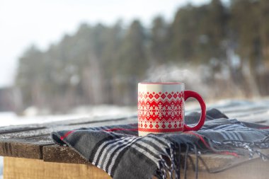 Dumanı tüten fincan sıcak kahve veya çay ayakta açık ahşap masa üzerinde karlı kış günü. Kış hafta sonu veya tatil, Noel sabahı, sağlıklı faaliyetleri açık kavramı.
