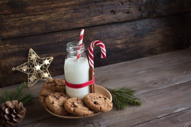 Kurabiye ve süt Noel Baba için. Geleneksel Noel ev yapımı çikolatalı kurabiye, şeker kamışı ve şişe süt rustik ahşap masa, kopya alanı üzerinde Noel dekorasyonu ile.