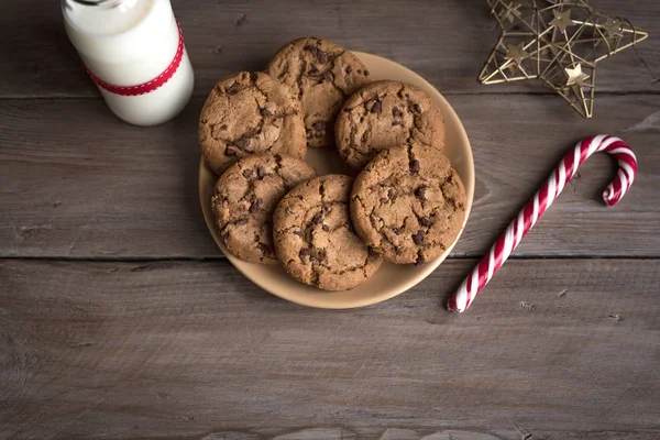 为圣诞老人准备的饼干和牛奶 传统的圣诞自制巧克力片饼干 糖果棒和一瓶牛奶与圣诞装饰质朴的木桌上 顶视图 — 图库照片
