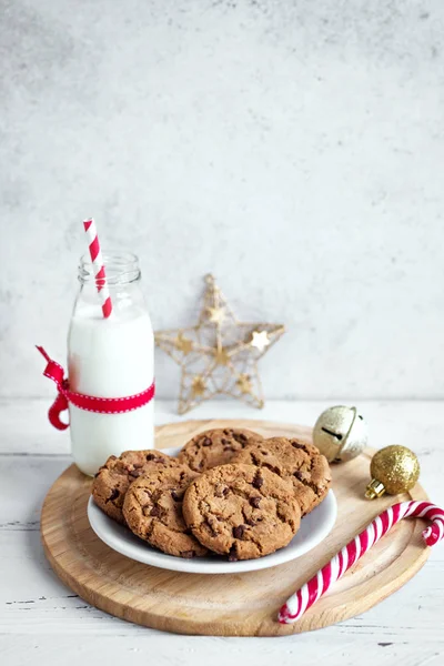 チョコレート チップ クッキーやサンタの牛乳 伝統的なクリスマス自家製クッキー キャンディの杖と白い木製のテーブルの上のクリスマスの装飾とミルクの瓶をコピー スペース — ストック写真