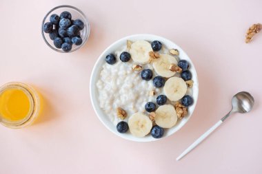 Ceviz, yaban mersini ve muz kase üzerinde pastel pembe - sağlıklı organik kahvaltı, meyve, bal ve fındık ile yulaf yulaf lapası