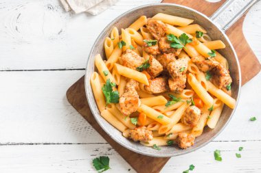 Domates soslu tavuk, maydanoz tavada penne makarna. Tavuk İtalyan penne makarna kopya alanı, İtalyan yemeği beyaz ahşap zemin üzerine.