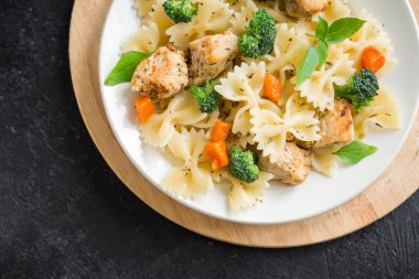 Farfalle makarna Tavuk ve sebze ile. Siyah arka plan, kopya alanı üzerine makarna salatası.