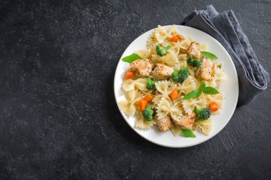 Farfalle makarna Tavuk ve sebze ile. Siyah arka plan, kopya alanı üzerine makarna salatası.