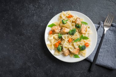 Farfalle makarna Tavuk ve sebze ile. Siyah arka plan, kopya alanı üzerine makarna salatası.