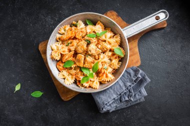 Farfalle makarna Tavuk ile domates sosu, fesleğen tavada. Tavuk İtalyan fiyonk makarna kopya alanı, ev yapımı İtalyan yemekleri ile siyah arka plan üzerinde.
