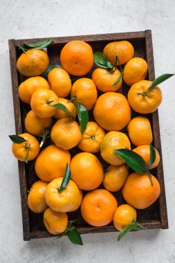 Mandalina (portakal, clementines, narenciye) beyaz taş arka planda, üstten görünüm kutusunda yeşil yaprakları ile.