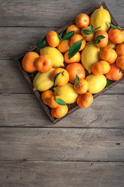 Çeşitli narenciye kutusunda - limon, mandalina, portakal yaprakları ile. Taze organik narenciye rustik ahşap arka plan, kopya alanı üzerinde.