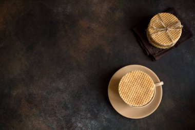 Hollandalı waffle, karamel ve sıcak içecek ile stroopwafel. Geleneksel ev yapımı Hollandalı waffle karanlık rustik masada.