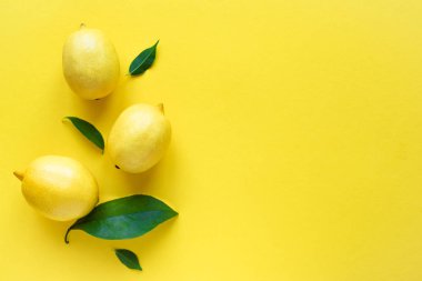 Limon sarı arka plan, üstten görünüm, üzerinde yeşil yaprakları ile alanı kopyalayın. Organik taze narenciye limon, en az kavramsal düz yatıyordu.