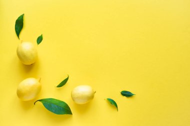 Limon sarı arka plan, üstten görünüm, üzerinde yeşil yaprakları ile alanı kopyalayın. Organik taze narenciye limon, en az kavramsal düz yatıyordu.