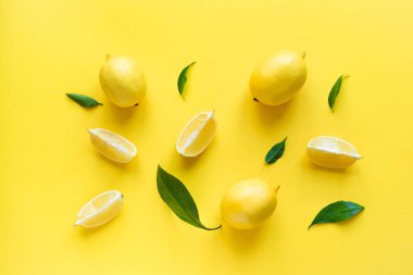 Limon sarı arka plan, üstten görünüm, üzerinde yeşil yaprakları ile lay düz. Organik taze narenciye limon, en az kavramsal düz yatıyordu.