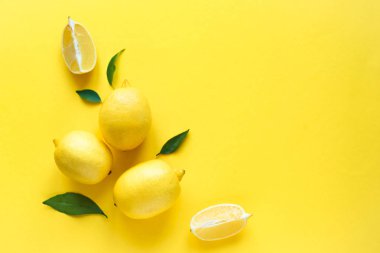 Limon sarı arka plan, üstten görünüm, üzerinde yeşil yaprakları ile alanı kopyalayın. Organik taze narenciye limon, en az kavramsal düz yatıyordu.