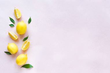 Pastel pembe, üstten görünüm, kopya alanı yeşil yaprakları ile limon. Organik taze narenciye limon, en az kavramsal düz yatıyordu.