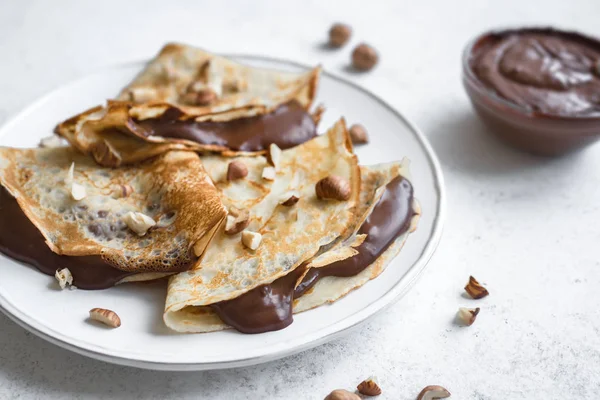 Crepes with chocolate spread and hazelnuts. Homemade thin crepes for breakfast or dessert, close up.