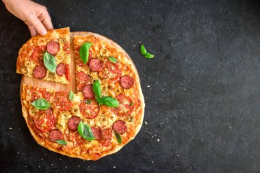 El İtalyan Pizza bir dilim alıyor. İtalyan Pizza ve elleri kadar yakın siyah arka plan, üstten görünüm, kopya alanı üzerinde.