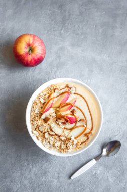 Elmalı turta güler yüzlü kase. Elma, tarçın, badem sütü, yulaf granola, tuzlu karamel ve baharatlar, üstten görünüm, kopya alanı ile güler yüzlü kase kahvaltı.