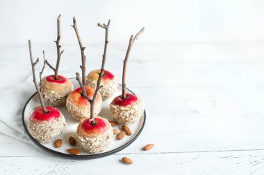 Beyaz ahşap arka planda, kış tatilleri için sopa üzerinde karamelli elma alan kopyalayın. Organik Snack, sağlıklı ev yapımı vegan tatlı - karamelli elma badem ile.