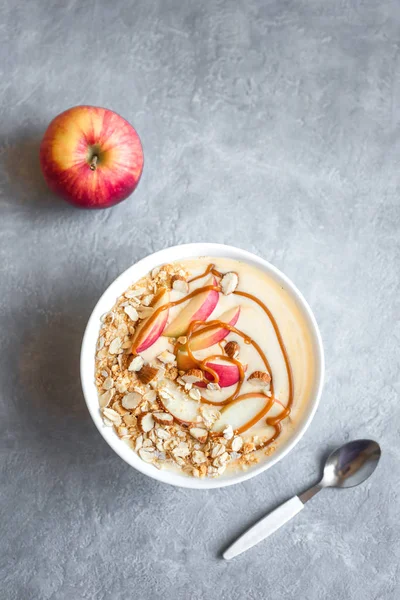 Apple Pie Smoothie Bowl. Breakfast smoothie bowl with apples, cinnamon, almond milk, oat granola, salted caramel and spices, top view, copy space.