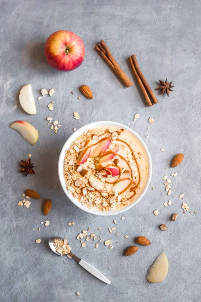 Apple Pie Smoothie Bowl. Breakfast smoothie bowl with apples, cinnamon, almond milk, oat granola, salted caramel and spices, top view, copy space.