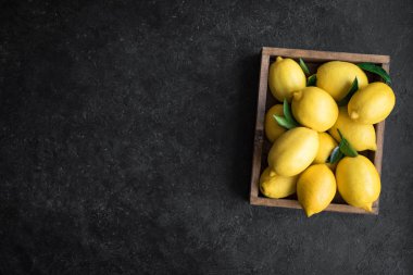 Limon siyah taş zemin, üstten görünüm, kopya alanı kutusunda yeşil yaprakları ile. Organik taze narenciye - limon.