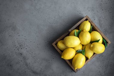 Limon gri taş arka plan, üstten görünüm, kopya alanı kutusunda yeşil yaprakları ile. Organik taze narenciye - limon.