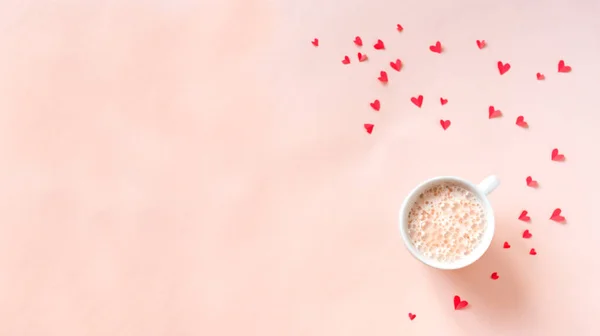 Cup of coffee and red hearts isolated on pink background, copy space. Minimal flat lay with cappuccino coffee for Valentine day, love and romance concept, top view.
