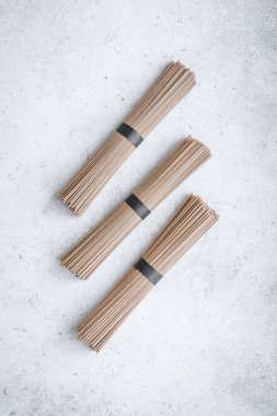 Soba noodle - geleneksel Asya gıda içerikler. Bohça-in buğday soba noodle beyaz beton zemin, üstten görünüm, kopya alanı.