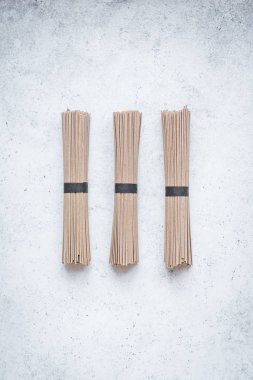 Soba noodle - geleneksel Asya gıda içerikler. Bohça-in buğday soba noodle beyaz beton zemin, üstten görünüm, kopya alanı.
