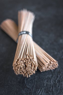 Soba noodle - geleneksel Asya gıda içerikler. Bohça-in buğday soba noodle siyah taş zemin, üstten görünüm, kopya alanı.