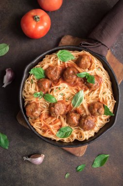 Köfte, domates sos ve taze fesleğen dökme demir tavada spagetti makarna. Sağlıklı ev yapımı makarna çeşitleri kopya alanı rustik zemin üzerine.