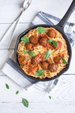 Köfte, domates sos ve taze fesleğen dökme demir tavada spagetti makarna. Beyaz ahşap arka plan kopya alanı ile sağlıklı ev yapımı İtalyan Makarna.