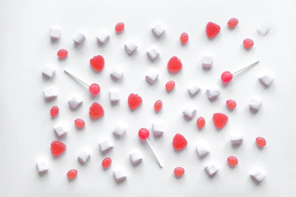Pink candies and marshmallows pattern on white background. Various pink sweets for Valentine Day as backdrop, top view.