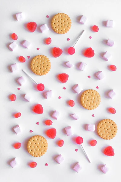 Pink candies, cookies and marshmallows pattern on white background. Various pink sweets for Valentine Day as backdrop, top view.