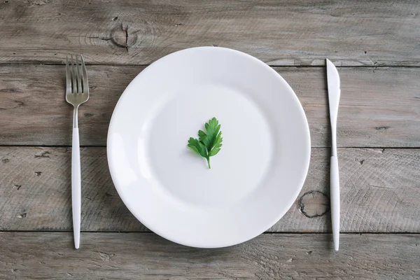 表设置与白色板材 现代餐具 叉子和刀 和小叶子新鲜欧芹在木质背景 上部看法 拷贝空间 纯素食生食概念 — 图库照片