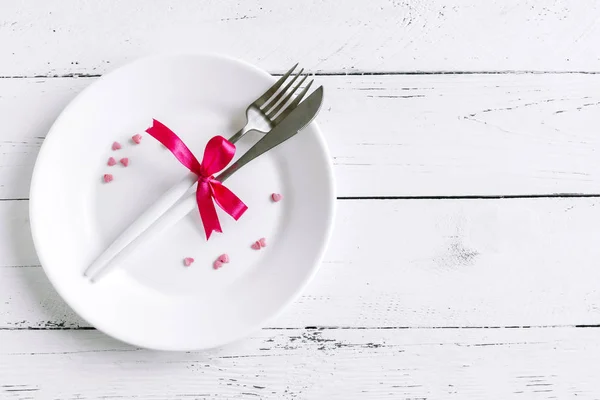 浪漫的桌子设置与白色板 现代餐具和红色丝带和心在白色的木制背景 顶部视图 复制空间 浪漫晚餐 婚礼概念 — 图库照片
