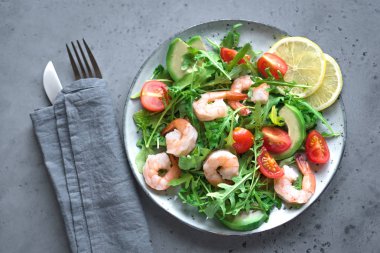 Roka ve domates gri taş zemin üzerine avokado karides salatası alanı kopyalayın. Sağlıklı diyet yeşil salata karides (karides), avokado, kiraz domates ve roka ile.