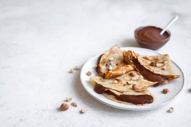Krep çikolata yayıldı ve fındık ile. Kahvaltı veya tatlı beyaz arka planda, kopya alanı için ev yapımı ince krep.