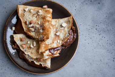 Krep çikolata yayıldı ve fındık ile. Kahvaltı veya tatlı rustik arka planda, kopya alanı için ev yapımı ince krep.