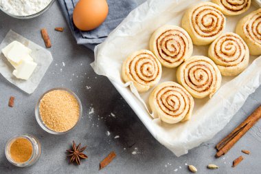 Rulo tarçın veya cinnabon, gri taş zemin üzerine pasta malzemeler ile ev yapımı tarifi çiğ hamur hazırlık şekerli geleneksel tatlı buns.