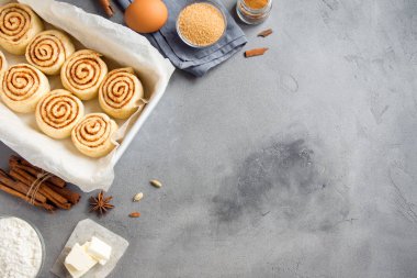 Rulo tarçın veya cinnabon, gri taş zemin, kopya alanı üzerine pasta malzemeler ile ev yapımı tarifi çiğ hamur hazırlık şekerli geleneksel tatlı buns.