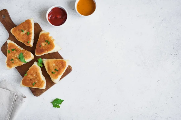 Deep fried meat pies with sauces, samsa, samosas, echpochmak - traditional meat stuffed pies or vegetarian pies on white background, copy space.